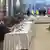 Negociadores sentados a una mesa con forma de U.