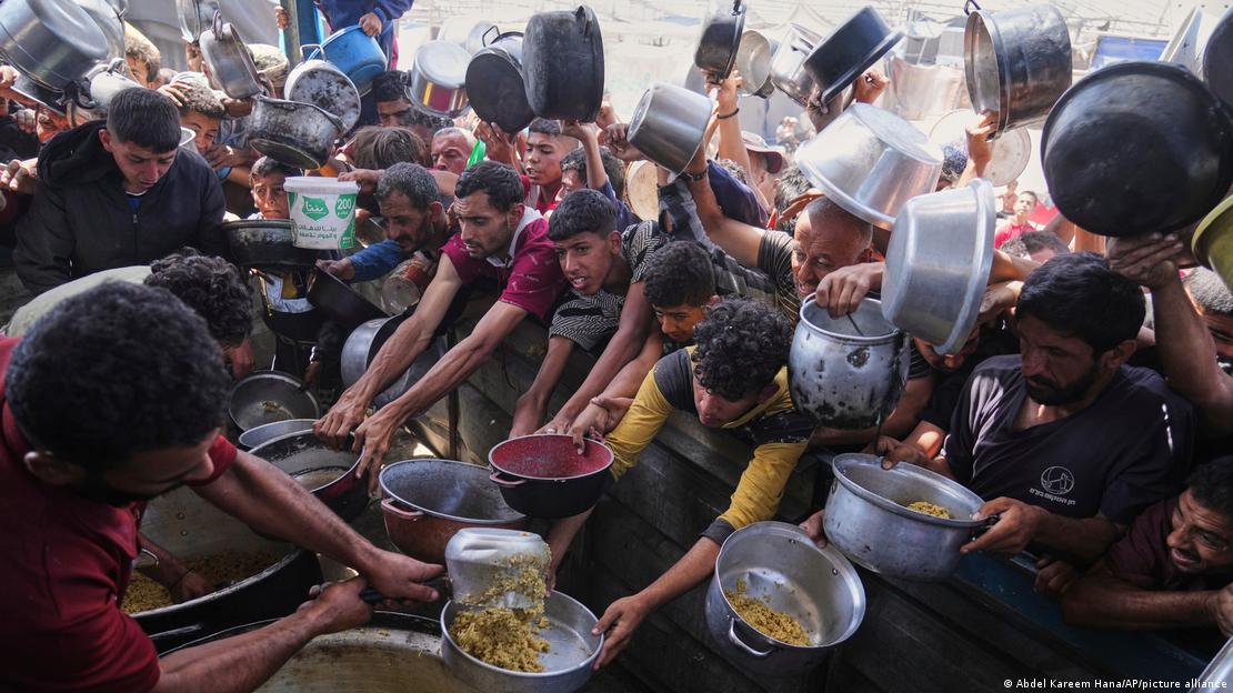 Pessoas com panelas tentam conseguir comida
