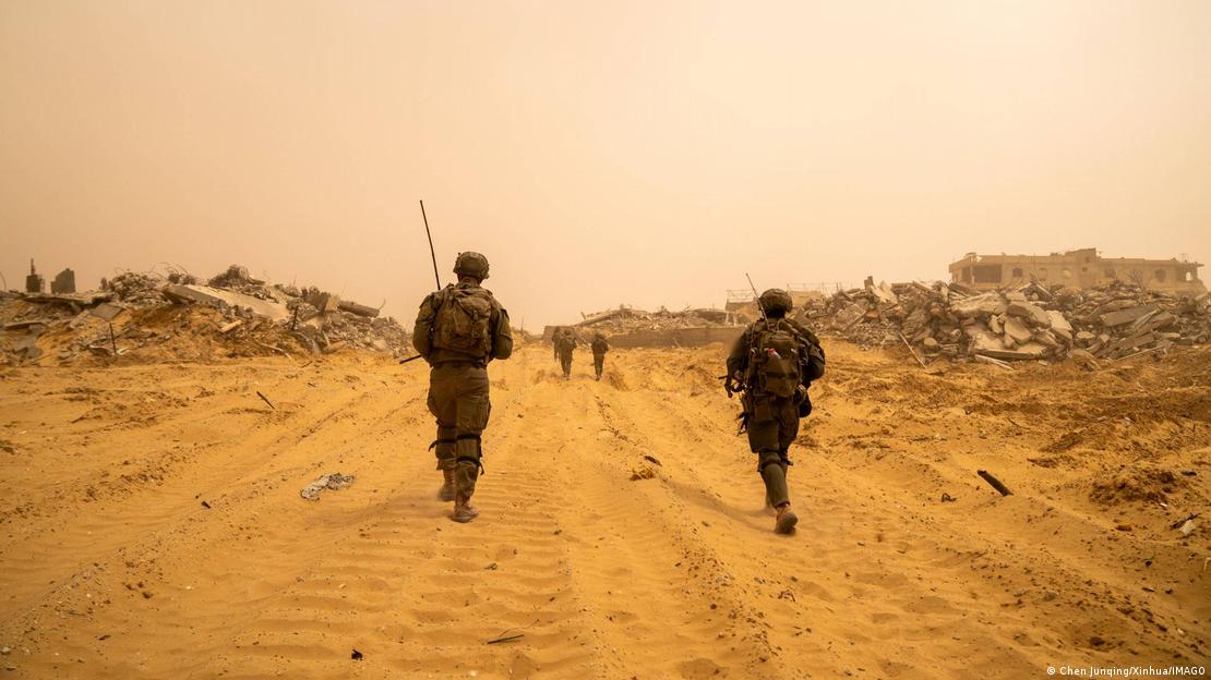 Gazastreifen 2025 | Israelische Soldaten gehen zwischen Trümmern her, auf dem Boden sind die Spuren von Panzerketten zu erkennen