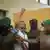Tanzania's opposition leader, Tundu Lissu, is escorted by a police officer as his supporters look on.