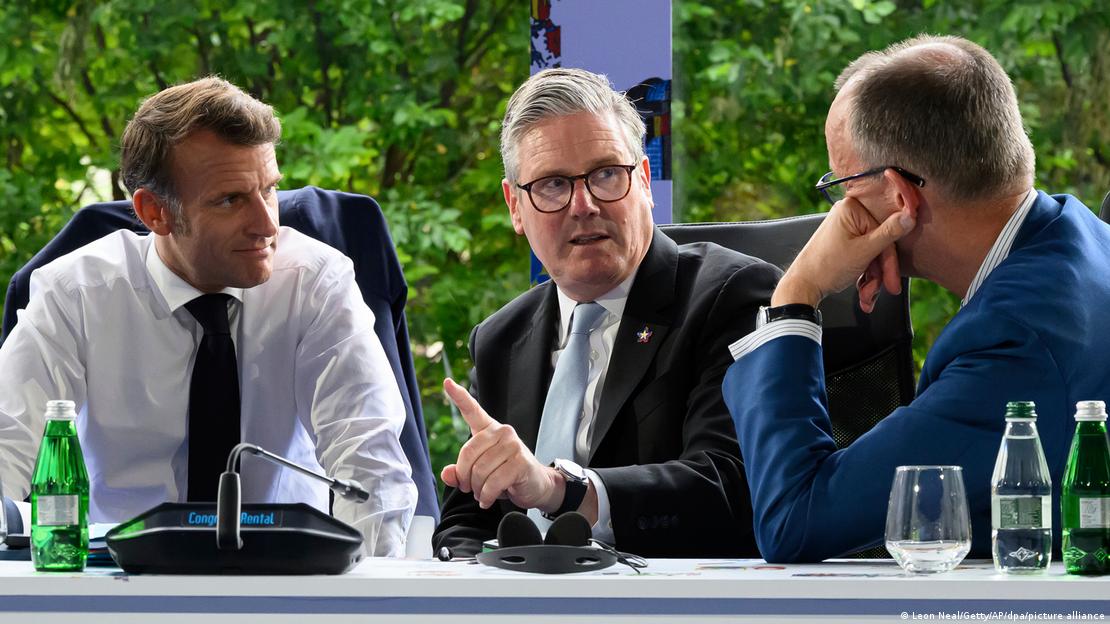 Staatspräsident Macron, Premier Starmer und Kanzler Merz (v.l.n.r) sitzen an einem Tisch und reden miteinander