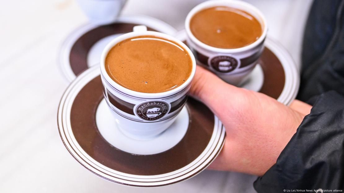 Pessoa carrega duas xícaras de café em uma mão Pessoa carrega duas xícaras de café em uma mão