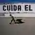 Un hombre pasa junto a un depósito de agua vacío en cuya pared puede leerse "Cuida el agua".