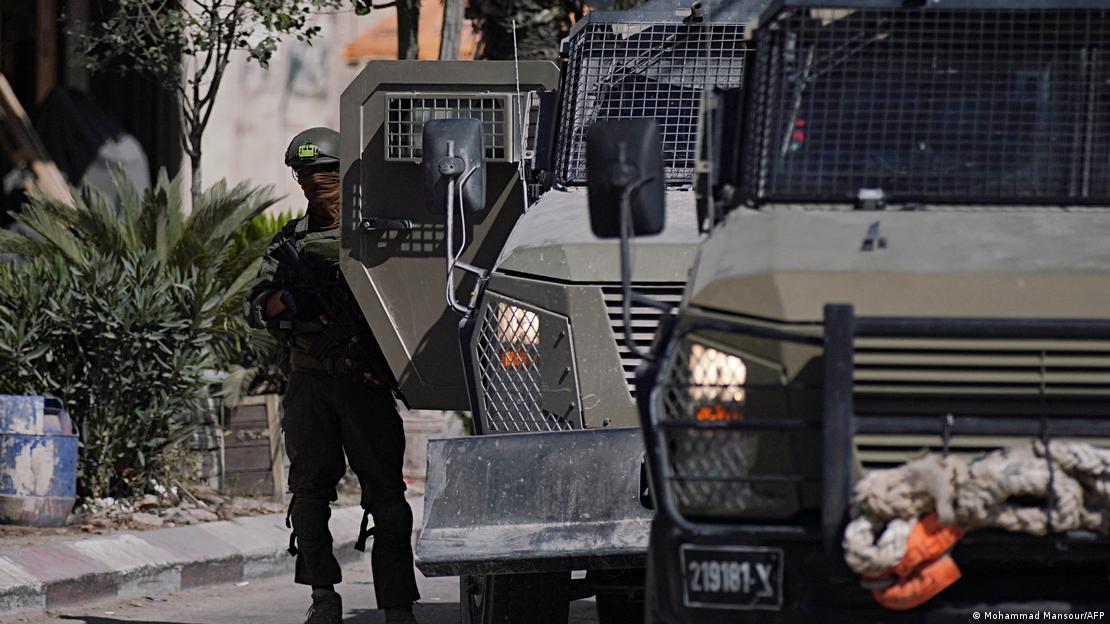 Batı Şeria kentinde askeri aracın yanında duran İsrail askeri.