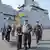 North Korean leader Kim Jong Un and his daughter, known as Ju-ae, walking with officials in an undated photo with a new 5,000-ton multipurpose destroyer navy ship in the background