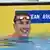 Greek swimmer Kristian Gkolomeev smiles in the pool with his goggles on his forehead