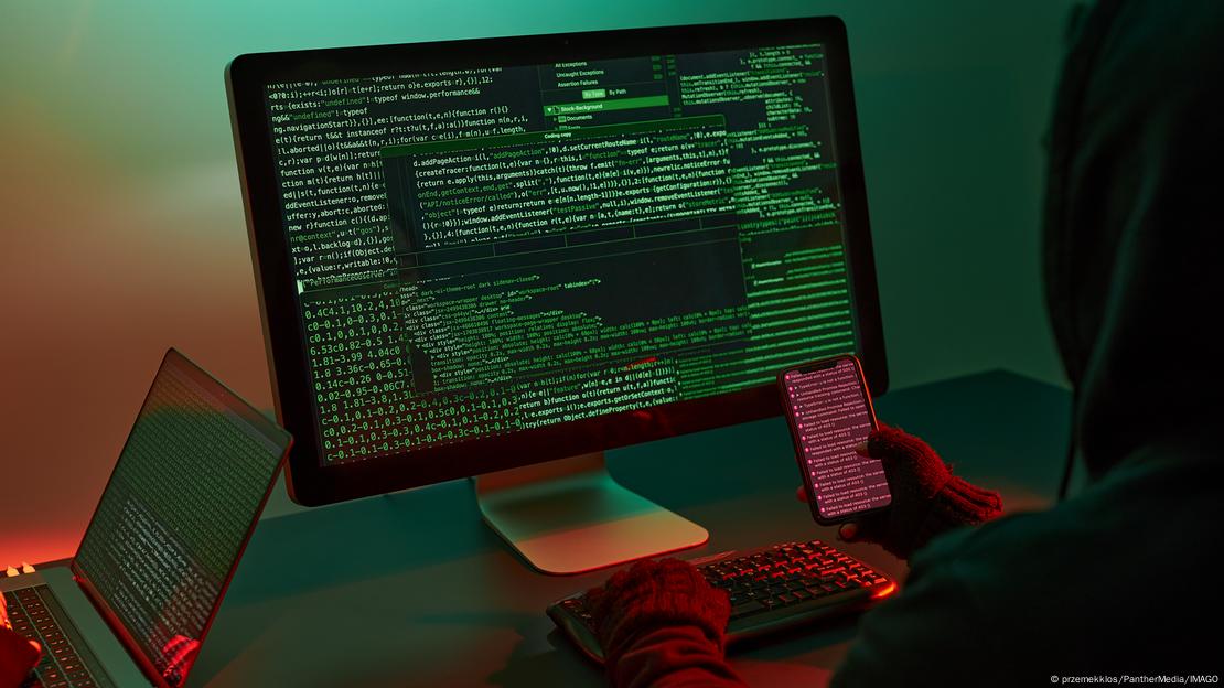 Një person duke punuar në errësirë me kompjuter dhe duke dërguar viruse apo duke krijuar profile “deepfake”. Një person duke punuar në errësirë me kompjuter dhe duke dërguar viruse apo duke krijuar profile “deepfake”.