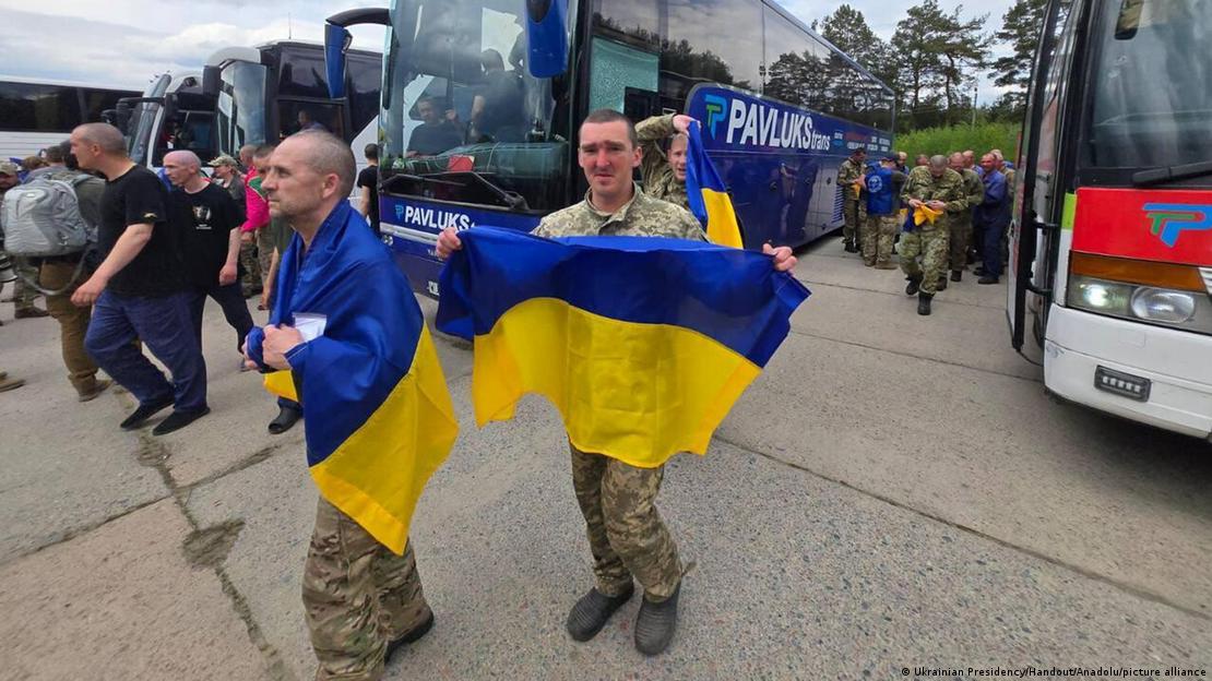 روسی قید سے رہائی پانے والے یوکرینی جنگی قیدیوں میں سے دو یوکرین واپسی پر اپنے ملک کے قومی پرچم کے ساتھ