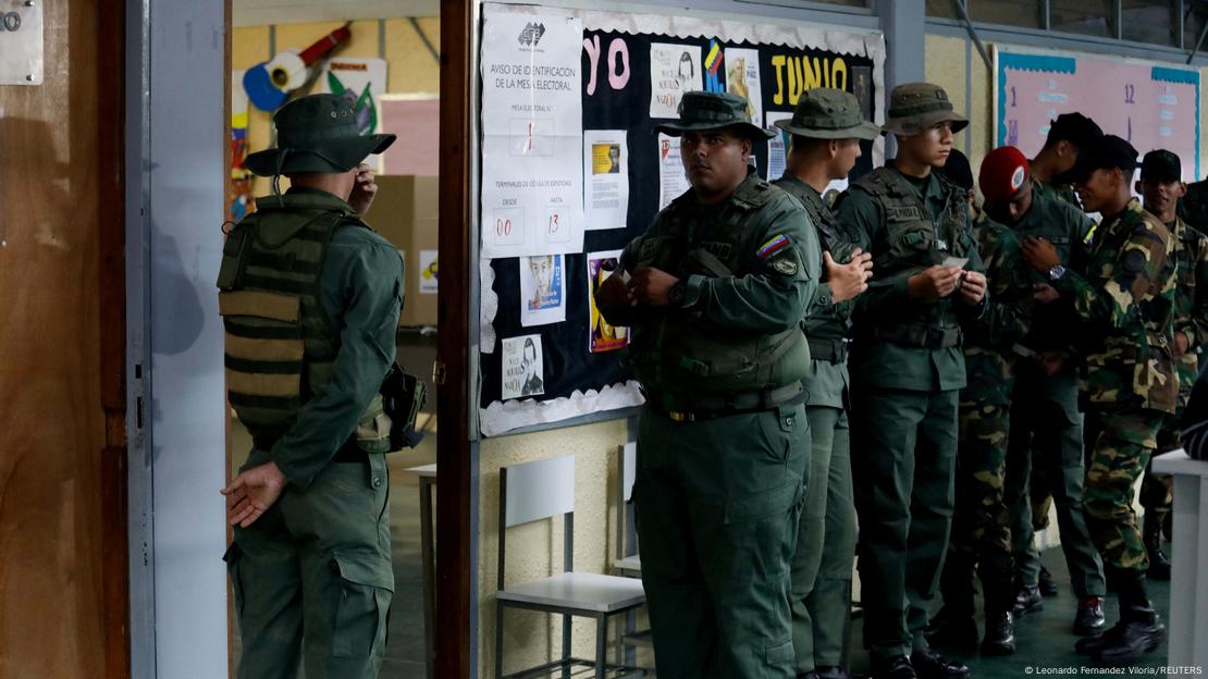 Un grupo de soldados uniformados guardan fila para votar en Caracas.