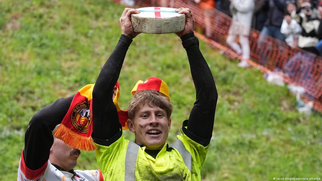 Großbritannien Gloucestershire 2024 | Tom Kopke hält nach dem Käserennen am Cooper's Hill einen Double-Gloucester-Käse in die Höhe (26.05.2025)