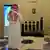 A Saudi Interior Ministry employee stands in front of a screen displaying the Absher mobile app logo at the ministry in Riyadh on February 19, 2019, about the Absher mobile app.
