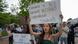 mujer sostiene pancarta a favor de estudiantes extranjeros en la Universidad de Harvard, en medio de manifestación.