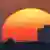 La silueta de la tanqueta y de un edificio de cinco alturas, recortadas contra el sol del atardecer.