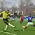 Spielszene: Ein Real Kashmir FC Spieler versucht in den Strafraum zu flanken, ein Gegenspieler versucht zu blocken; im Hintergrund Mitspieler und Zuschauerränge