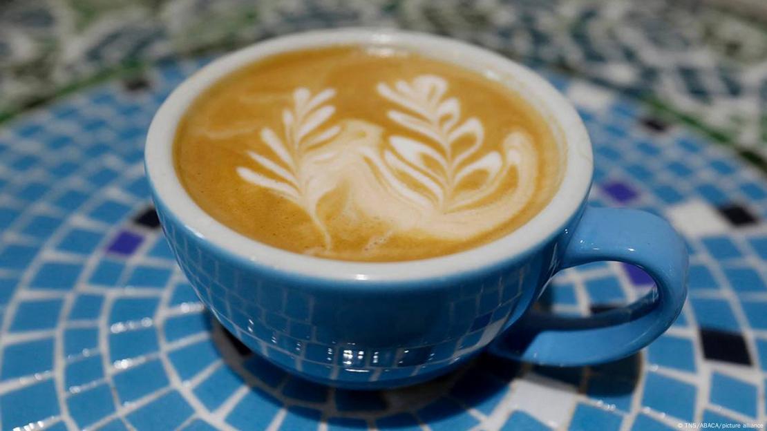 Cappuccino com latte art de folhas em xícara azul Cappuccino com latte art de folhas em xícara azul