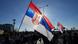 The sun shines through a large Serbian flag being carried during a protest. People, some carrying flags or signs, walk along a road, Belgrade, Serbia, June 1, 2025 The sun shines through a large Serbian flag being carried during a protest. People, some carrying flags or signs, walk along a road, Belgrade, Serbia, June 1, 2025