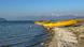 Yellow fishing boats lie on the shore of a lake (Great Prespa Lake). There is a red-and-white buoy in the water. In the distance are snow-topped mountains Yellow fishing boats lie on the shore of a lake (Great Prespa Lake). There is a red-and-white buoy in the water. In the distance are snow-topped mountains