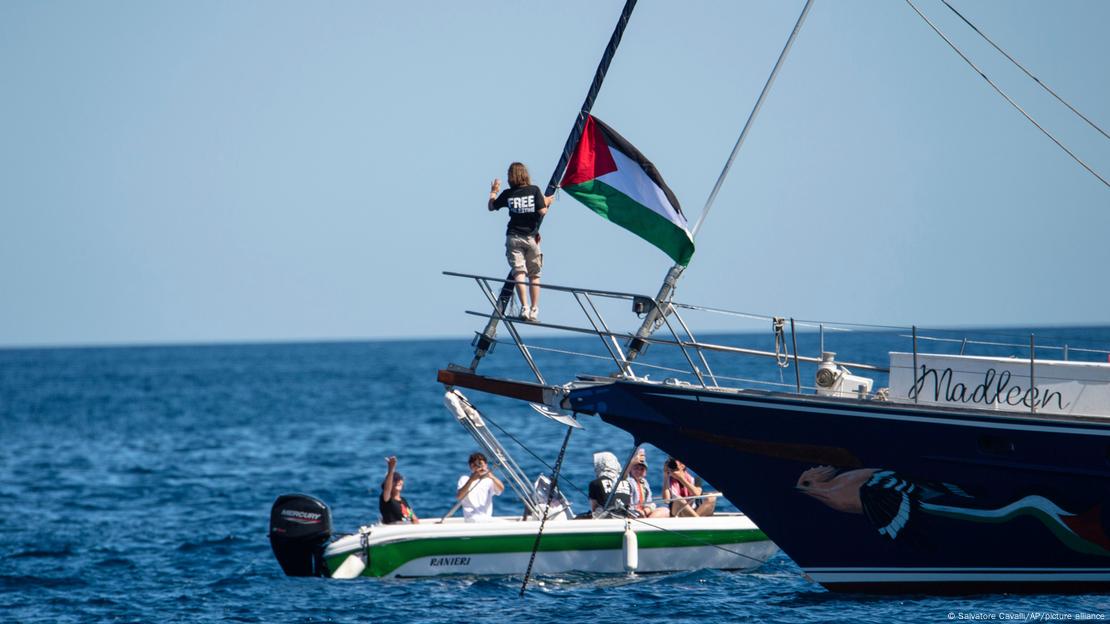 Greta Thunberg junto a una bandera palestina tras subir a bordo del barco Madleen y antes de zarpar hacia Gaza junto con activistas.