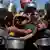 Children and women are squashed in a crowd, holding out pans as they struggle to get donated food at a community kitchen in Khan Younis