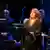 A woman stands and sings in front of an orchestra