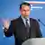 Radosław Sikorski w garmiturze i krawacie mówi na scenie do mikrofonu