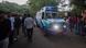 An ambulance passes by a crowd of onlookers on a tree-lined street An ambulance passes by a crowd of onlookers on a tree-lined street