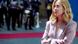 A woman in a pale lilac suit and blonde hair (Italian Prime Minister Giorgia Meloni) looks upward as a military band can be made out behind her in a photo taken on May 17,2025 A woman in a pale lilac suit and blonde hair (Italian Prime Minister Giorgia Meloni) looks upward as a military band can be made out behind her in a photo taken on May 17,2025