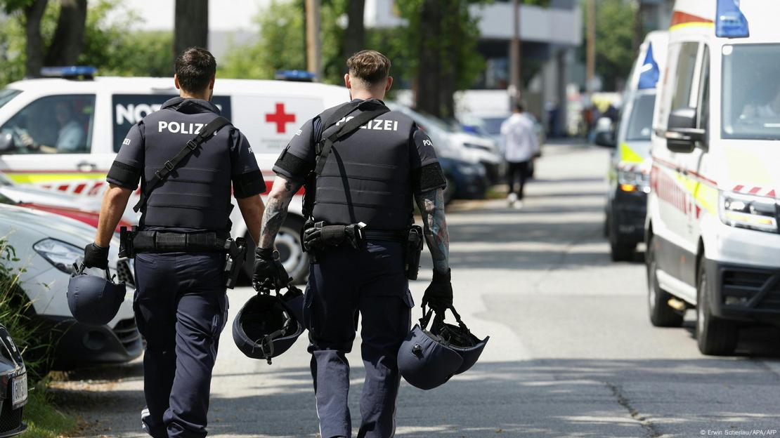 Dos policías caminan entre ambulancias y vehículos policiales en el operativo policial en las inmediaciones de la escuela secundaria en Graz. Dos policías caminan entre ambulancias y vehículos policiales en el operativo policial en las inmediaciones de la escuela secundaria en Graz.