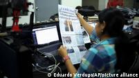 A woman at a desk looks over a paper in Spanish