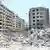 Escombros de un edificio destruido. A su lado, varios bloques de edificios en pie.