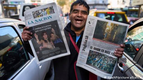 Miguel Robledo ríe mientras vende en la calle periódicos con portadas que informan sobre la condena de la expresidenta argentina Fernández de Kirchner.