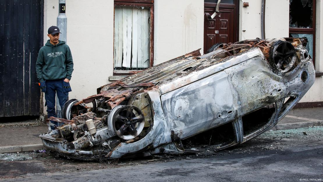 Un hombre junto a un vehículo quemado en Ballymena, Irlanda del Norte. Un hombre junto a un vehículo quemado en Ballymena, Irlanda del Norte.