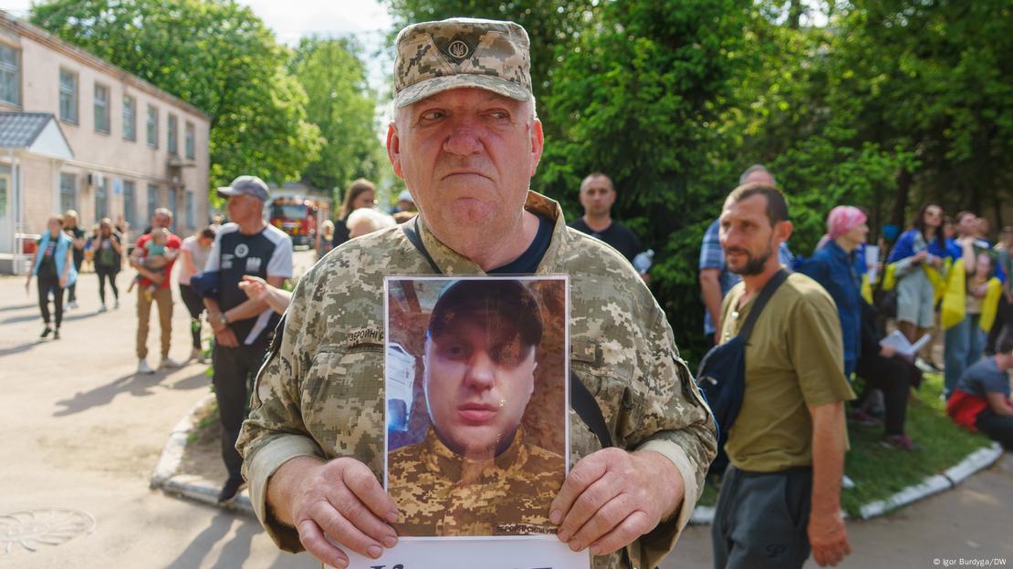 Пожилой мужчина с фотографией сына, пропавшего на войне в Украине