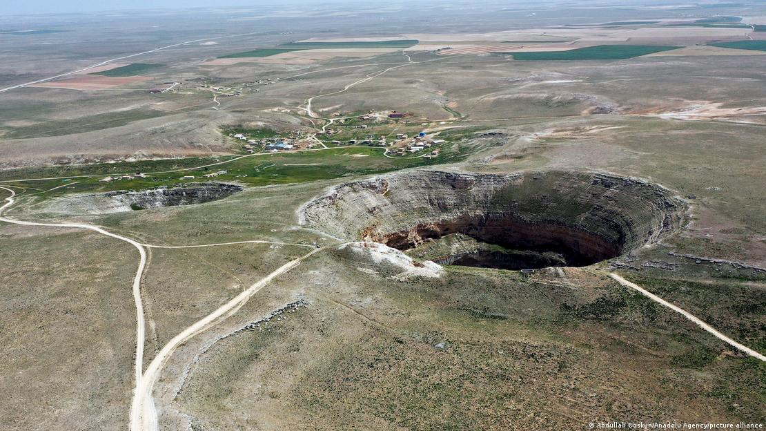 Imagem de drone de uma grande cratera em terreno numa planície