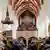Innenraum mit Publikum, im Hintergrund der Thomanerchor auf der Orgelempore.
