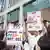 Two protesters in white coats outside a bank hold up placards reading 'Invest in biodiversity not oil'