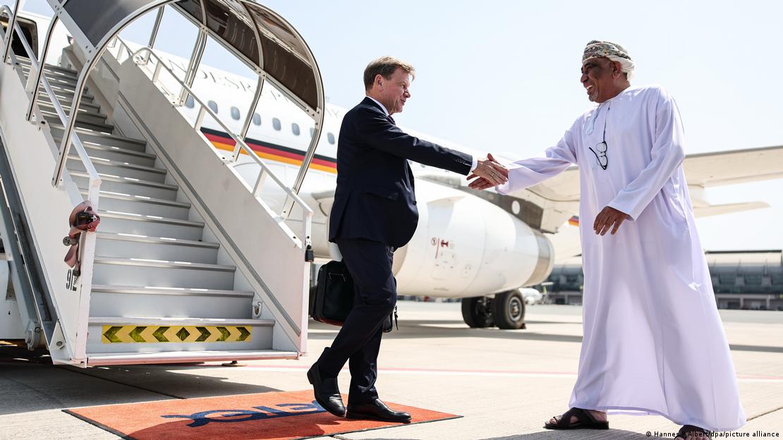 Deutschlands Außenminister Wadephul begrüßt einem Mnan in einem weißen Gewand vor einem Flugzeug