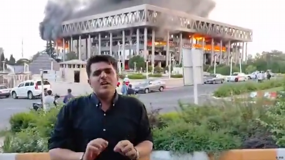 El edificio en llamas detrás de un periodista que informa en directo del ataque. El edificio en llamas detrás de un periodista que informa en directo del ataque.