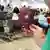 Eine Person hält einen deutschen Reisepass in der Hand, im Hintergrund der Flughafen-Wartebereich 