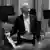 Dier Pianist Alfred Brendel sitzt bekleidet mit einem Frack und schaut nach oben.
