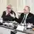 Trzej mężczyźni siedzą przy stole, w środku prezydent Rosji Władimir Putin