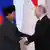 Prabowo Subianto and Vladimir Putin shake hands in front of flags