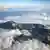 Vista aérea sobre o Monte Rinjani, que tem formações rochosas ao redor de um lago levando até a cratera de um vulcão