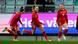 Three Wales players celebrate a goal wearing red kit Three Wales players celebrate a goal wearing red kit