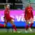 Three Wales players celebrate a goal wearing red kit