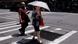 A woman walks over a road with a sun umbrella A woman walks over a road with a sun umbrella