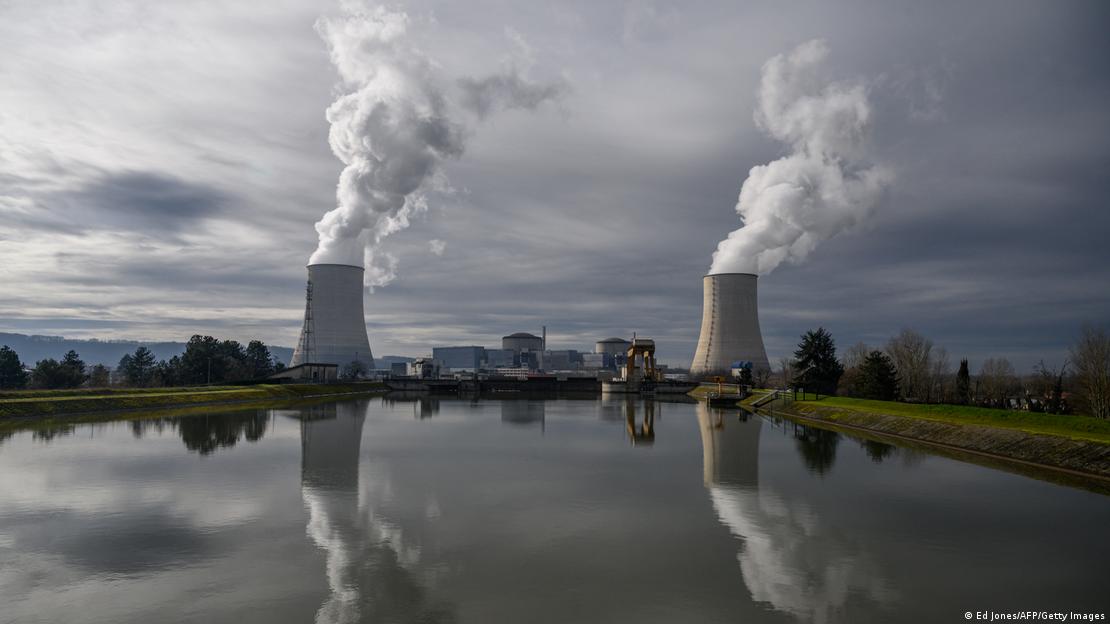 Duas chaminés de reatores de usina nuclear espelhadas em lago