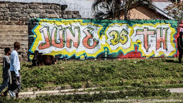 People walk past a graffiti mural marking the first anniversary of anti-government demonstrations seen on a wall.