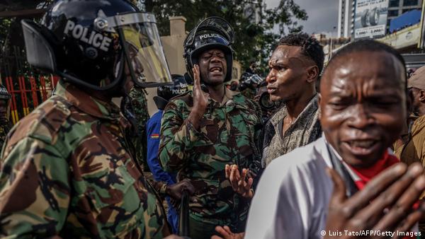 A member (C) of the Kenya Police Service gestures while interacting with demonstrators marching in downtown Nairobi.