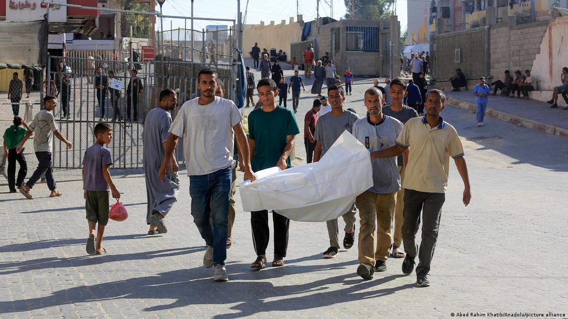 Homens palestinos carregam corpo de homem que foi morto ao tentar receber ajuda humanitária; registro do dia 25 de junho de 2025 feito em Khan Yunis